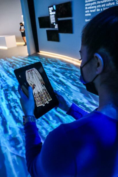Woman holding ipad with Benaki AR app in World Expo 2020