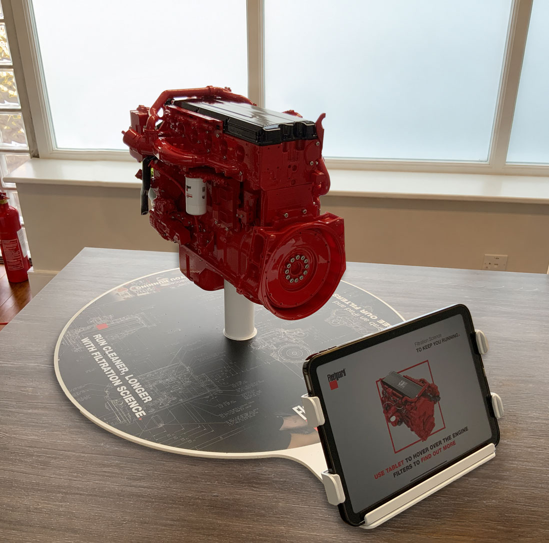 Red engine model display on a circular Fleetguard platform with an attached iPad holder.