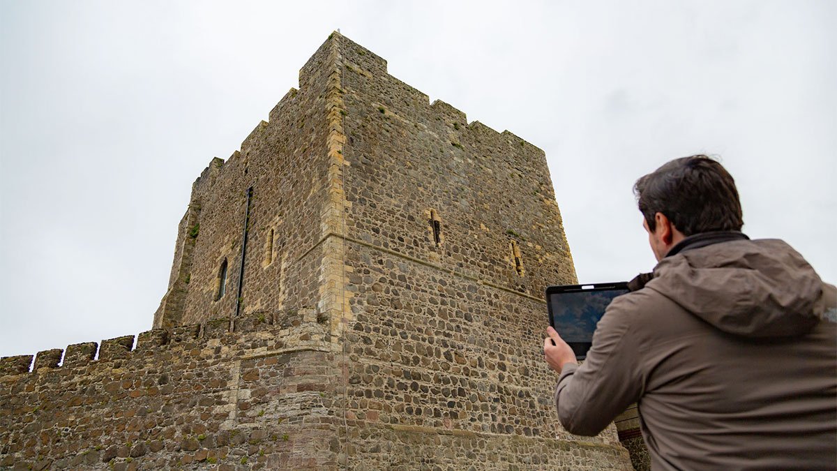 Person holding iPad testing immersive AR heritage site reconstruction app for Carrickfergus Castle, Tourism Northern Ireland