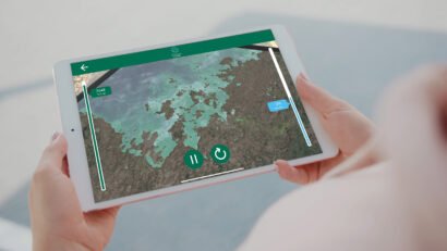 Person holding tablet visualising Augmented reality app that showcases 3d model terrain flooding. Climate change AR app