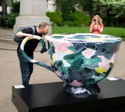 A man posing for a photo beside a mug sculpture featured in the London Heritage AR Trail.