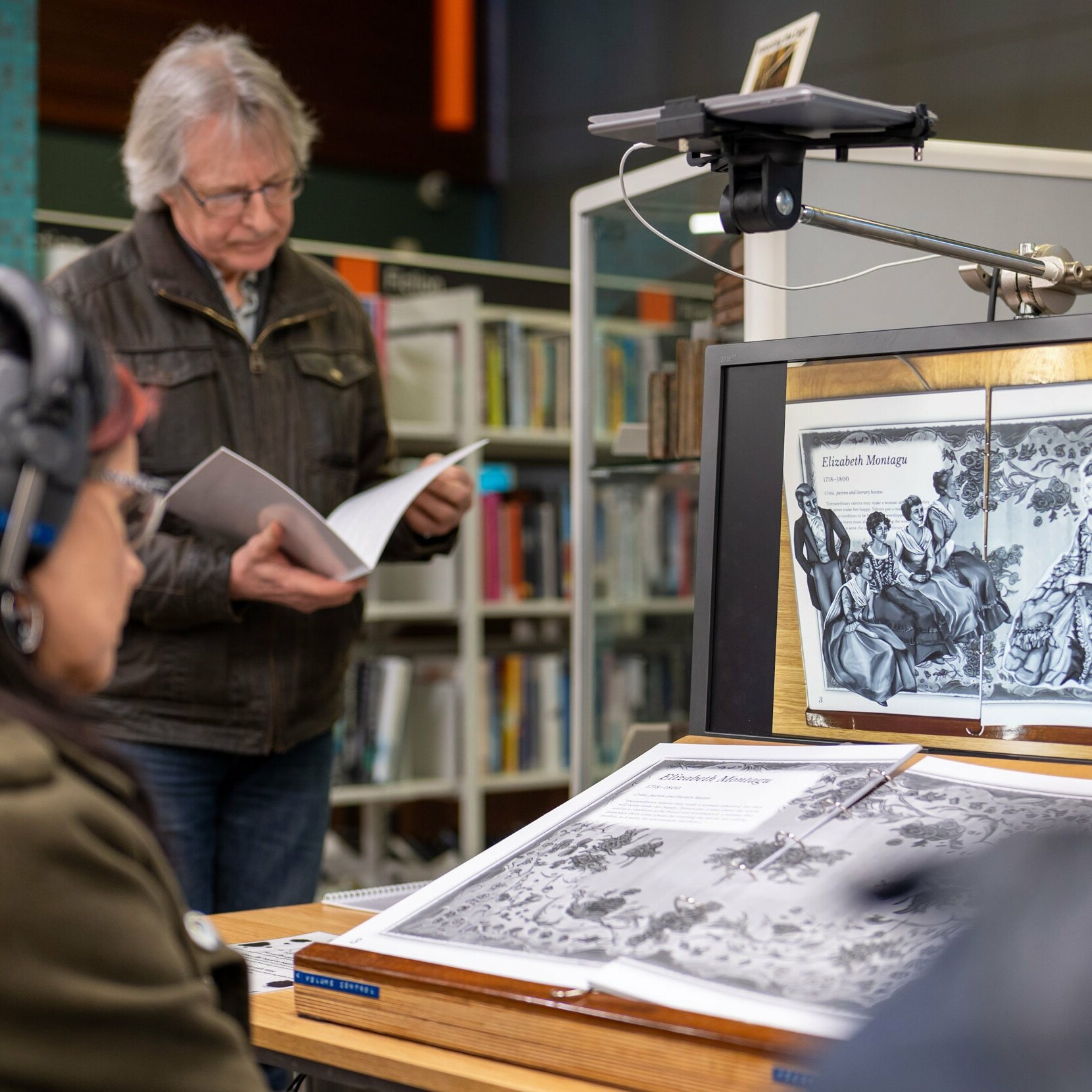 Woman reading AR book, Unlocking The Cage Augmented Reality experience at Exeter Library for international women's day