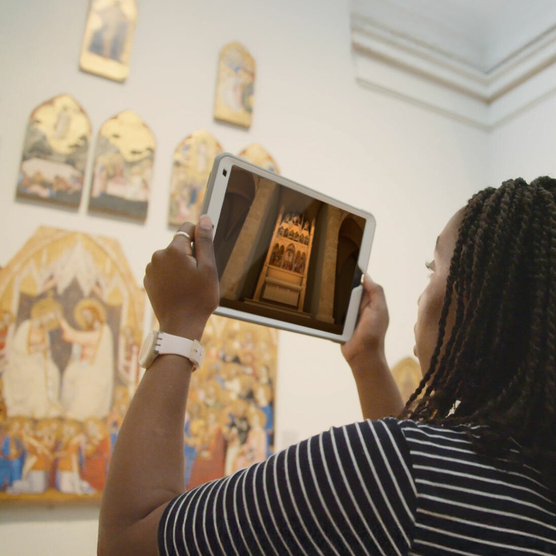Woman holding iPad looking at reconstruction in Augmented reality AR of a church in National Gallery museum. Augmented reality for museums and heritage