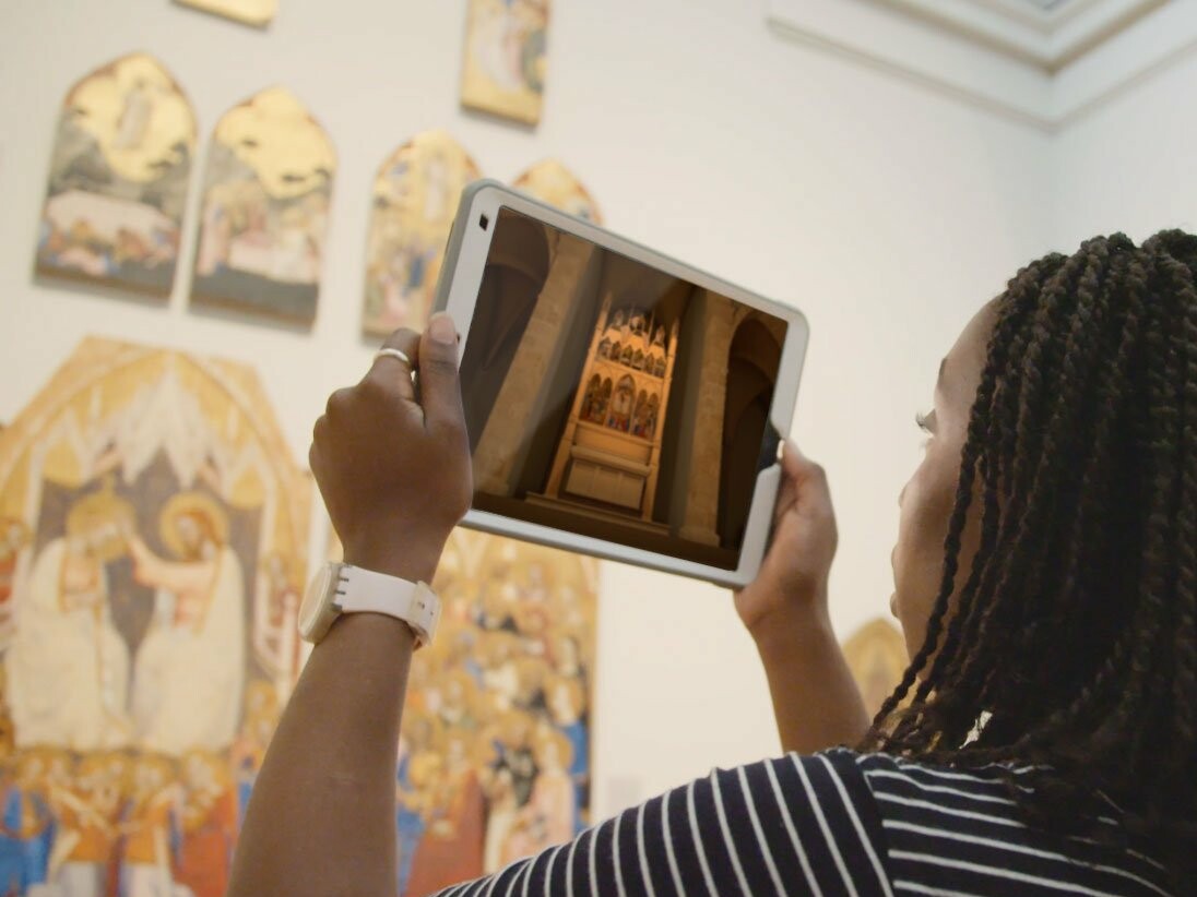 Woman holding iPad looking at reconstruction in Augmented reality AR of a church in National Gallery museum. Augmented reality for museums and heritage