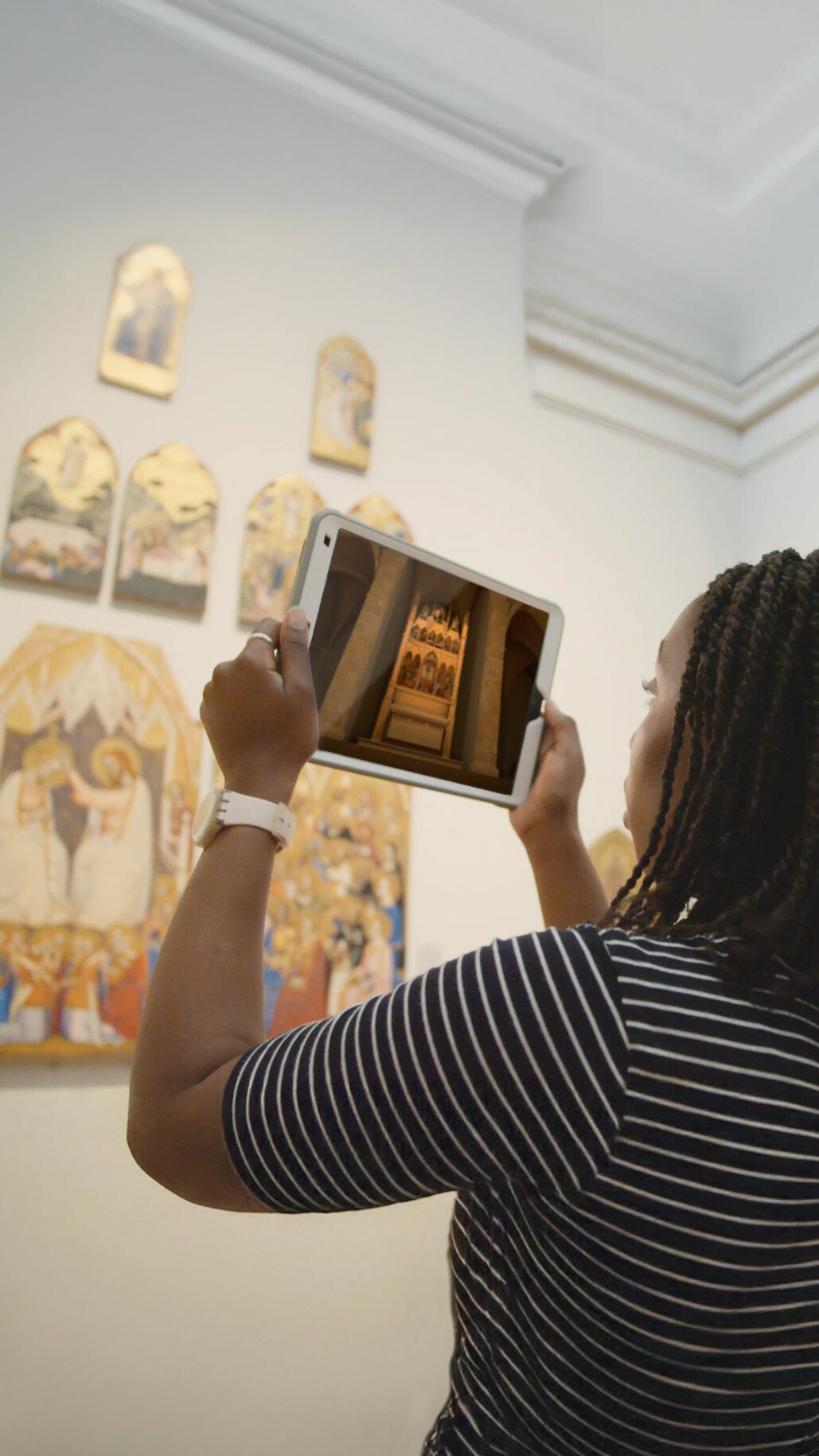 Woman holding iPad looking at reconstruction in Augmented reality AR of a church in National Gallery museum. Augmented reality for museums and heritage