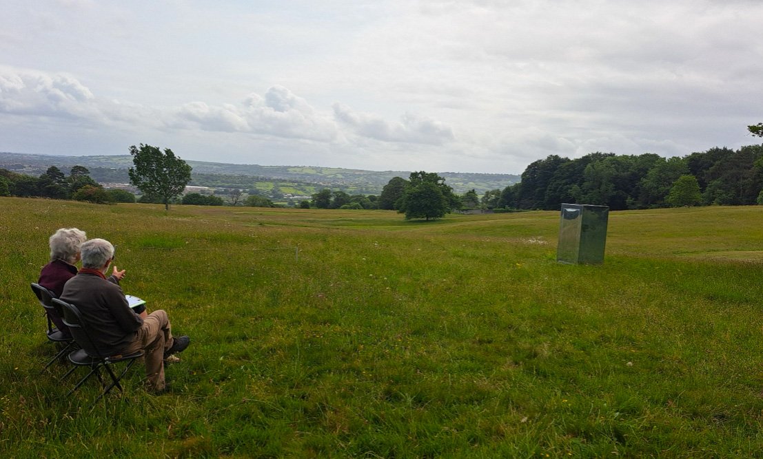 Two people sitting in Ashton Court looking at a Mirrorbox, interactive sculpture for I would be here if I could project