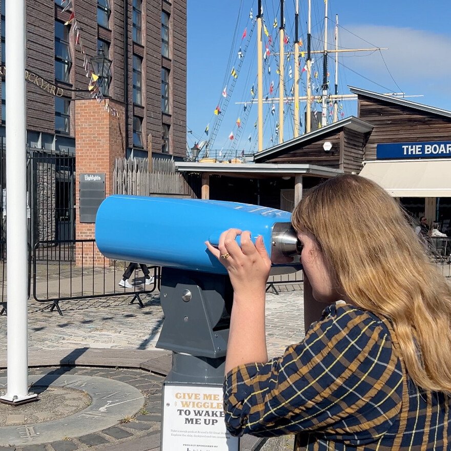 Person looking through SSGB Virtual reality binoculars installed in Bristol Harbourside. Tempting ticket sales with VR binoculars at SSGB