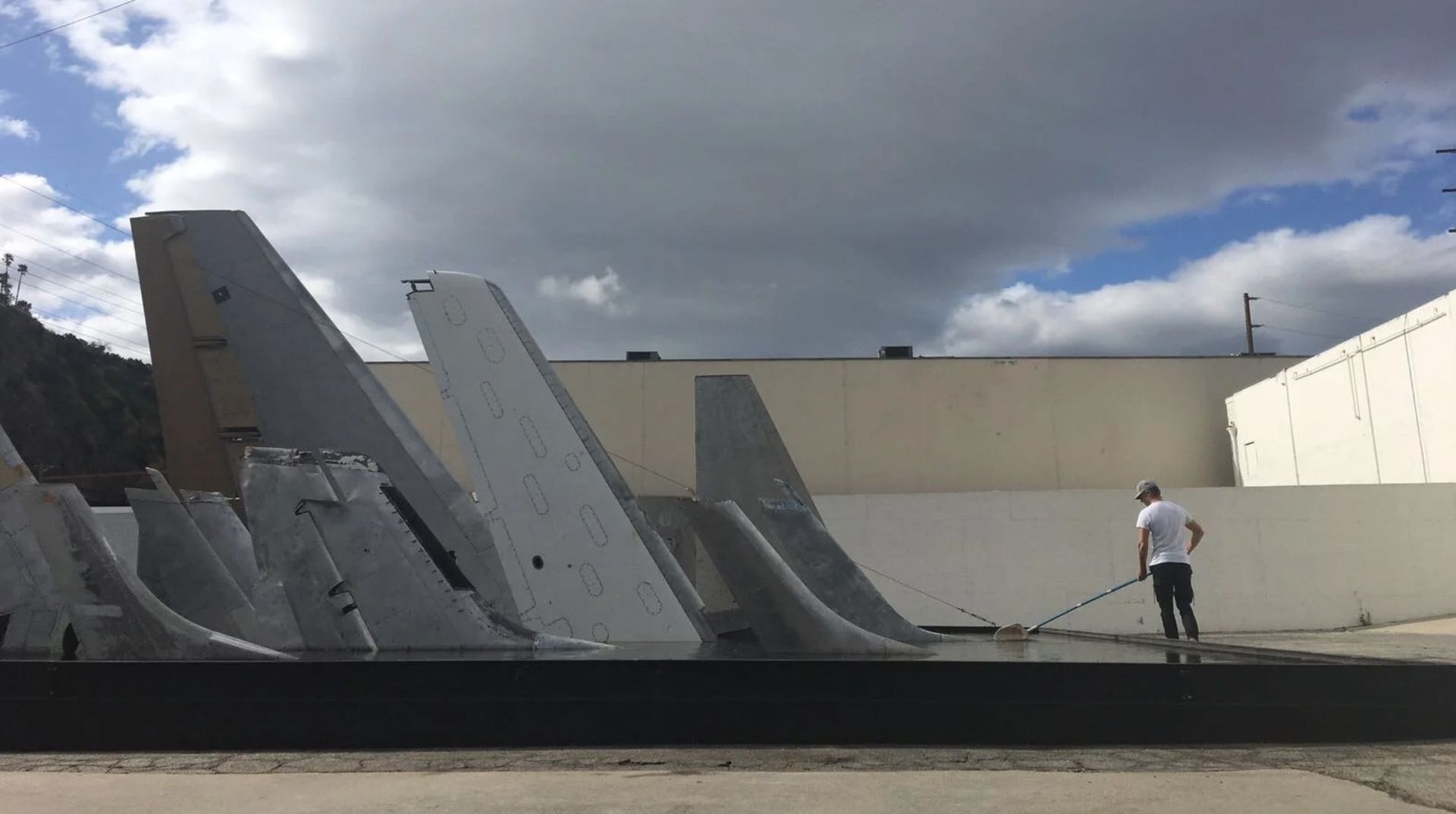 Simon Birch, Clear Air Turbulence, 2016-17, Site specific installation: Salvaged airplane tails in steel-framed pool, Aluminum, steel, paint, water, ink. Installation view.