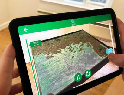 Person holding tablet visualising Augmented reality app that showcases 3d model terrain flooding. Climate change AR app