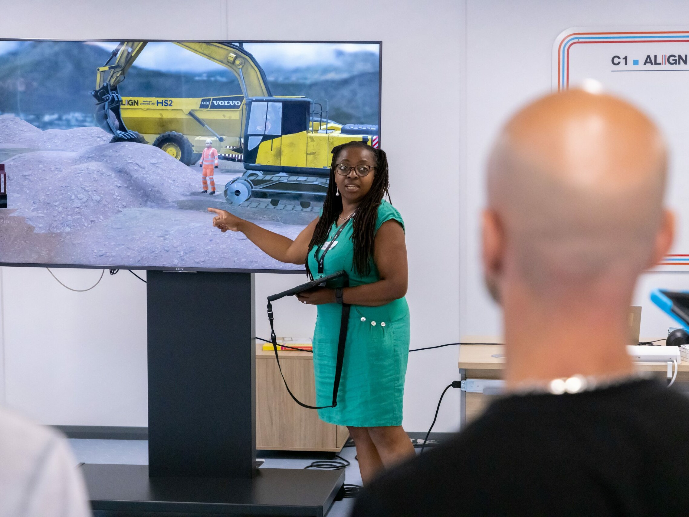 Trainer demonstrating an AR construction site safety induction using immersive training technology, with HS2 construction machinery displayed on screen.